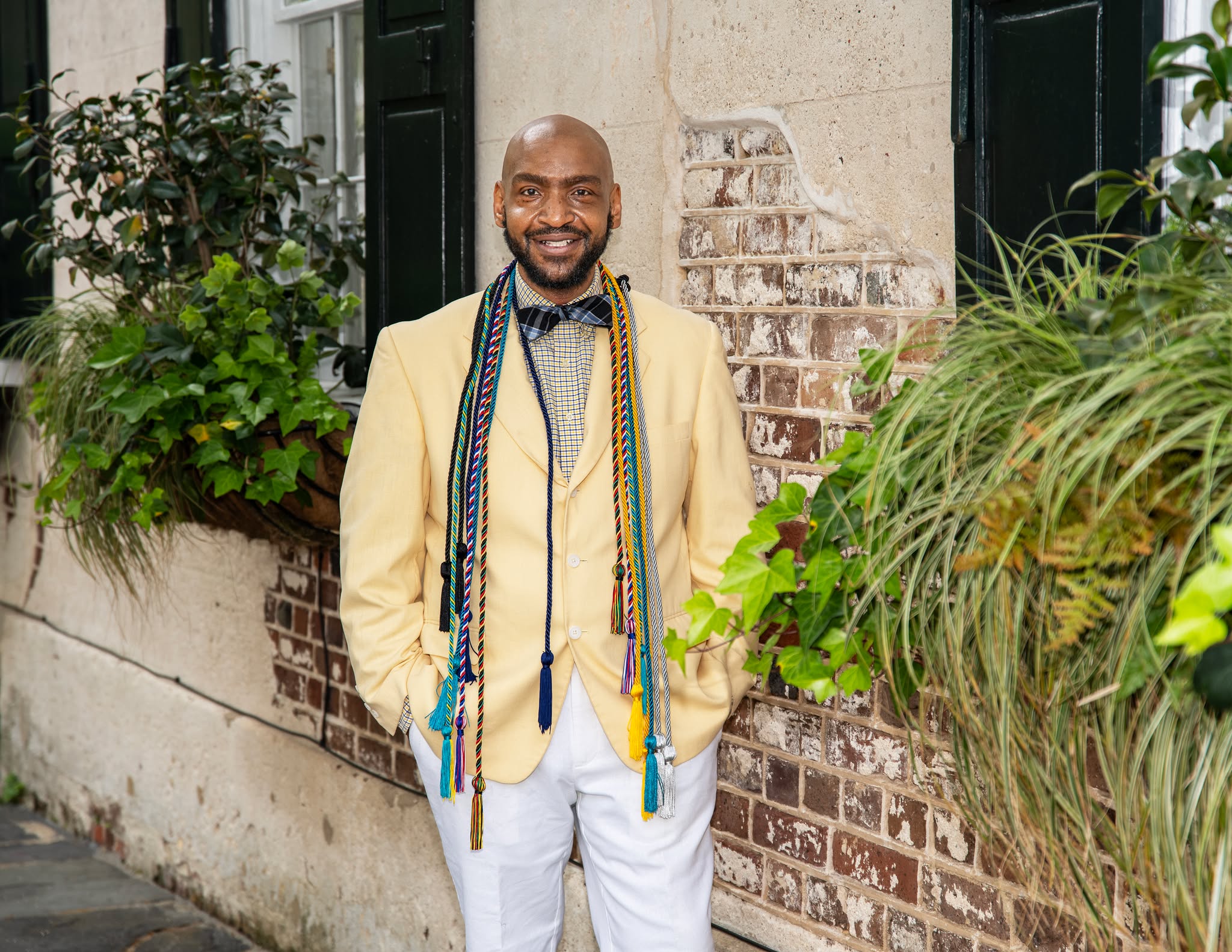 Joseph DeSio wearing a yellow suit with colorful graduation honor cords