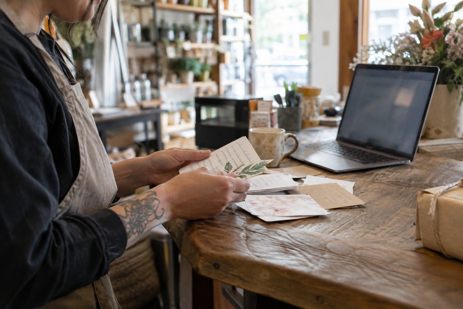 Shop owner reviewing customer notes beside a laptop at a small business counter